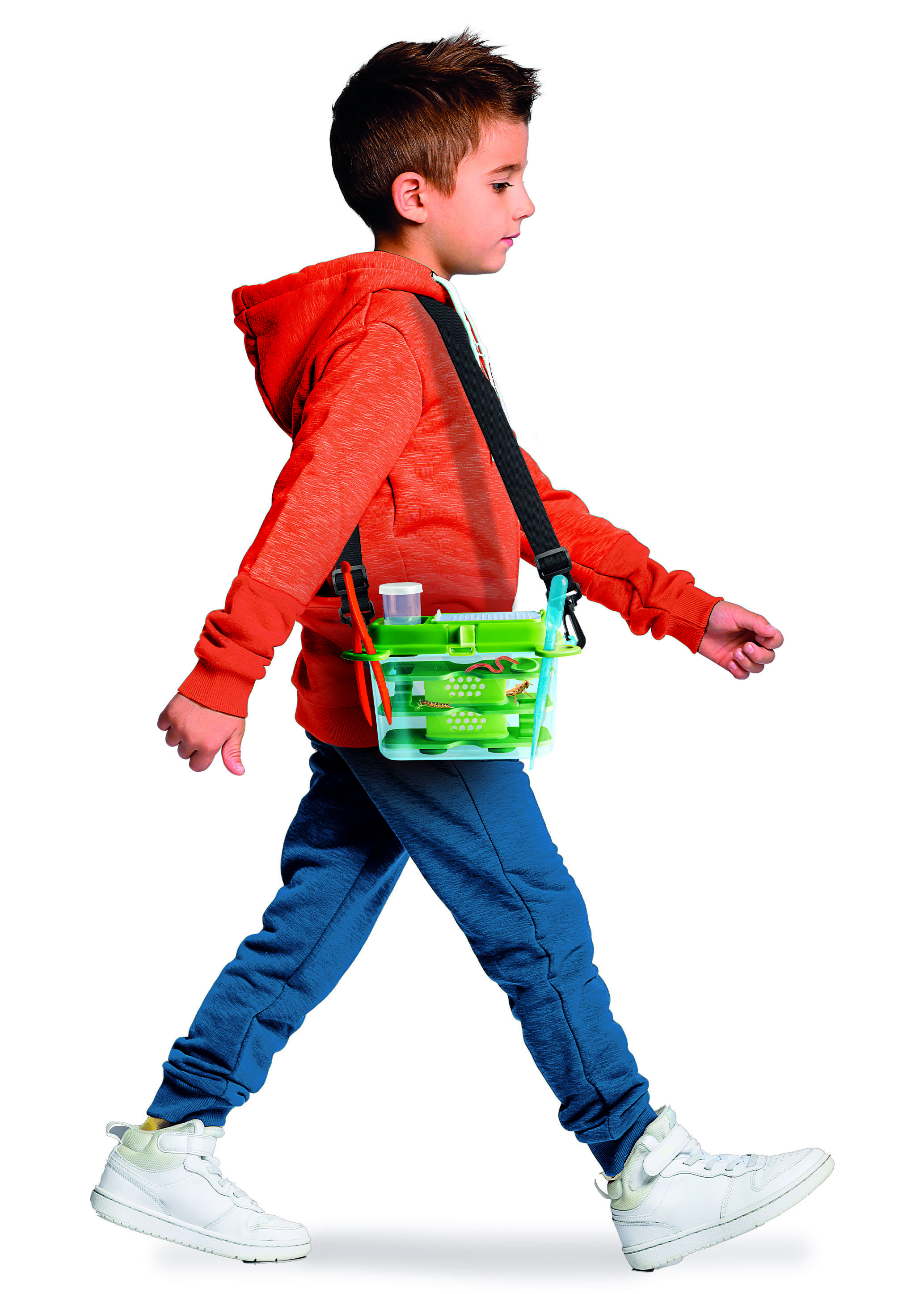 Un niño con sudadera naranja, pantalones azules y zapatos blancos lleva un kit atrapainsectos verde en el hombro.