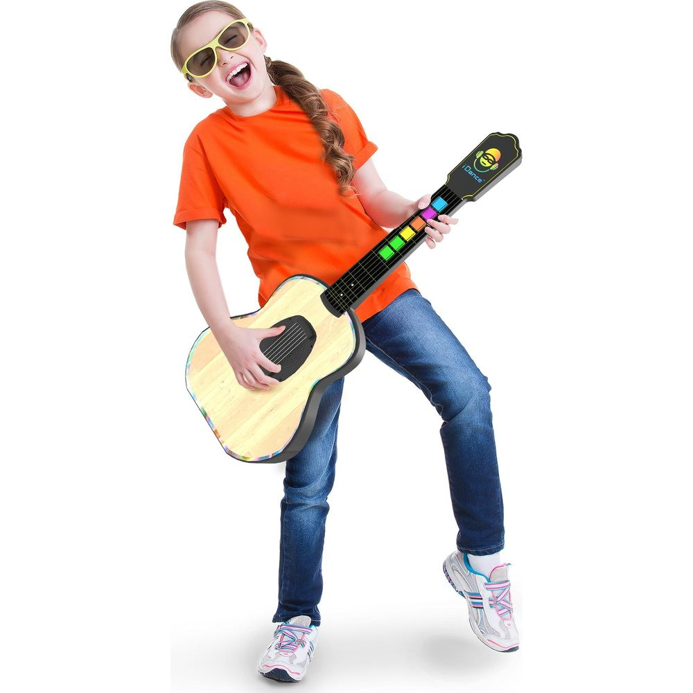 Une jeune fille en t-shirt orange et jean joue joyeusement d'une guitare jouet colorée avec des lunettes de soleil.