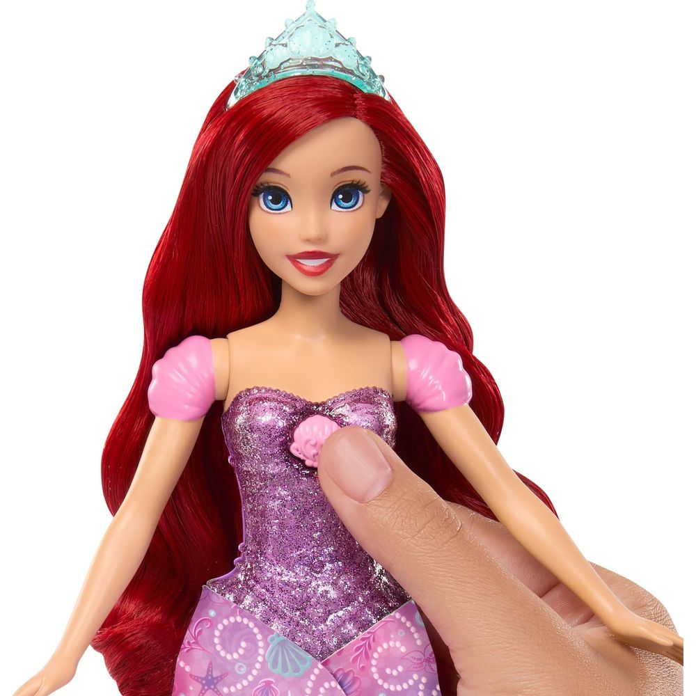 Nahaufnahme einer Ariel-Puppe mit roten Haaren und Diadem in Glitzerkleid, eine Hand drückt auf ihr Mieder.