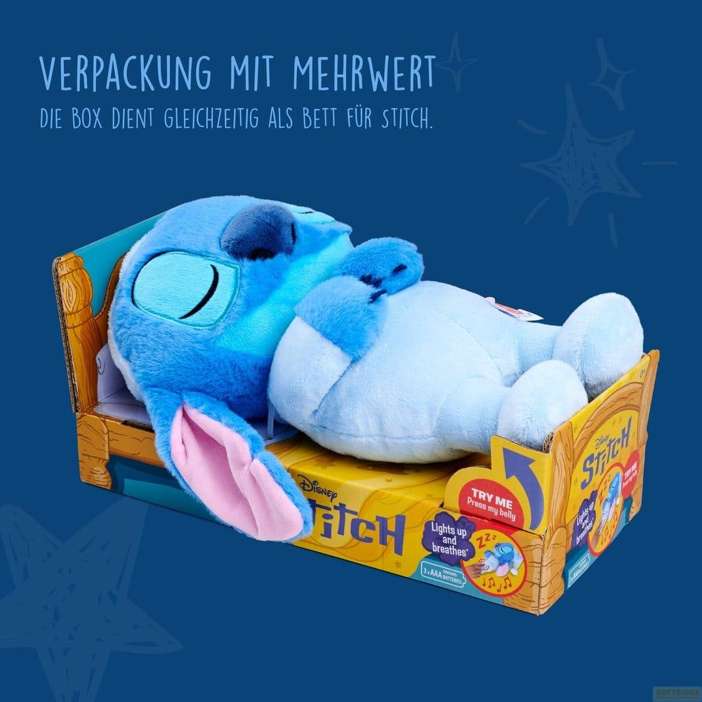Ein blauer Stitch-Plüschtier liegt in einer Pappschachtel, die wie ein Bett aussieht, vor blauem Hintergrund.