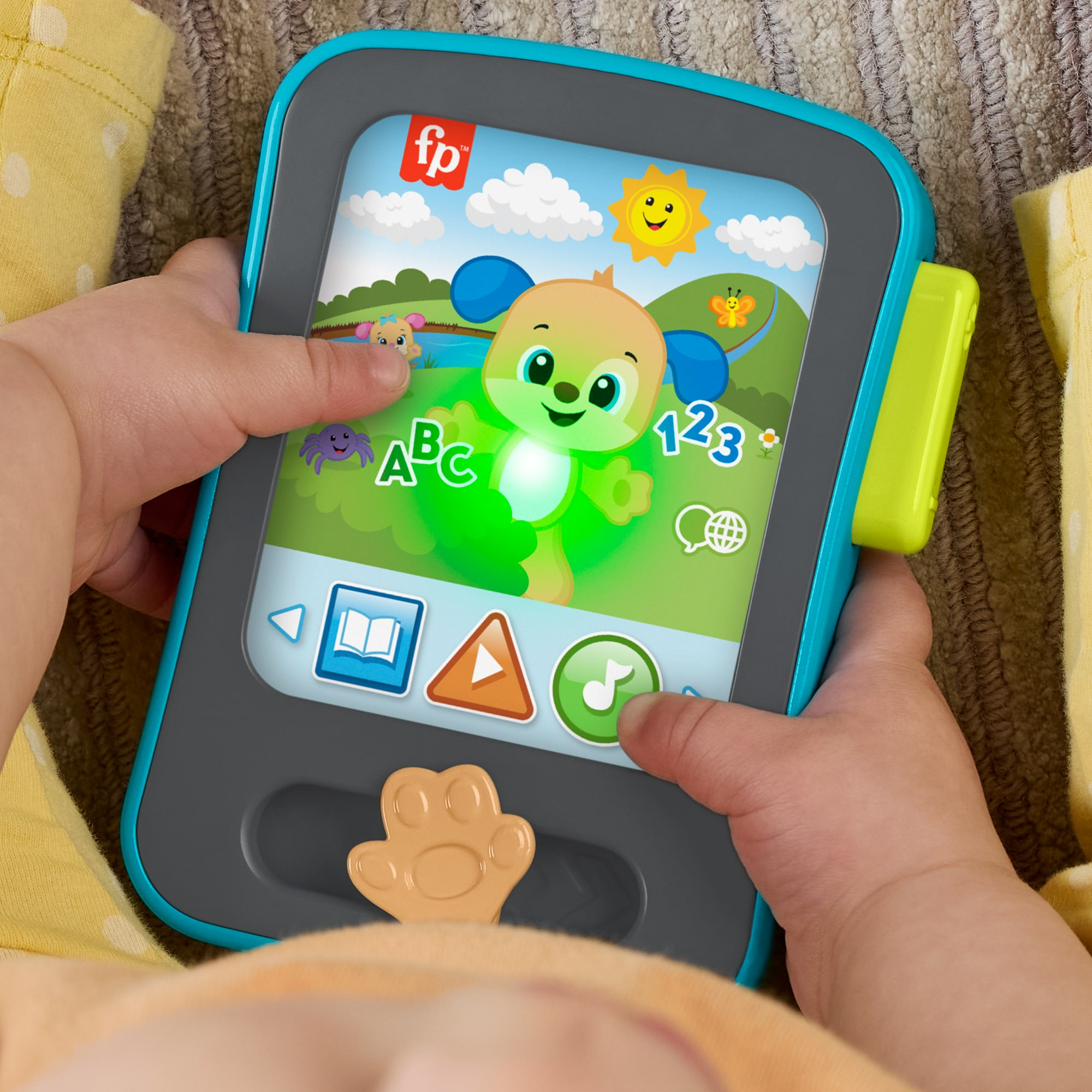 Ein Baby hält ein blau-graues Fisher-Price-Lernspielzeug mit bunten Grafiken und Lichtern auf dem Bildschirm.