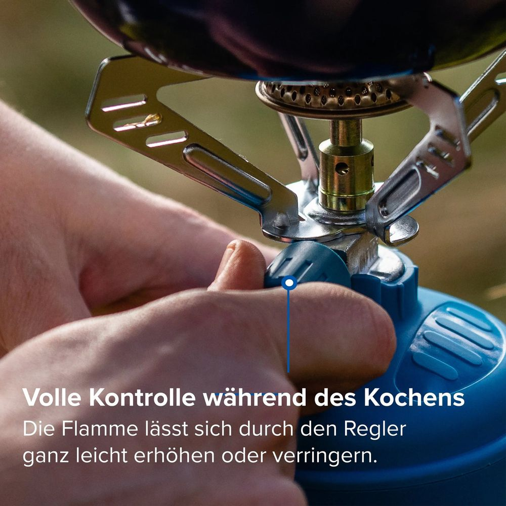 Hände bedienen das blaue Regelventil eines kleinen, silbernen Campingkochers, auf dem ein Kochtopf steht.