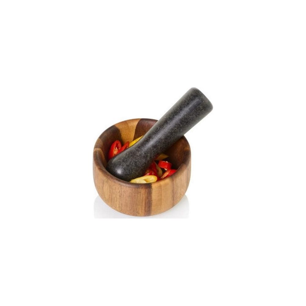 Ein hölzerner Mörser mit dunklem Stößel und roten und gelben Chilis drinnen.