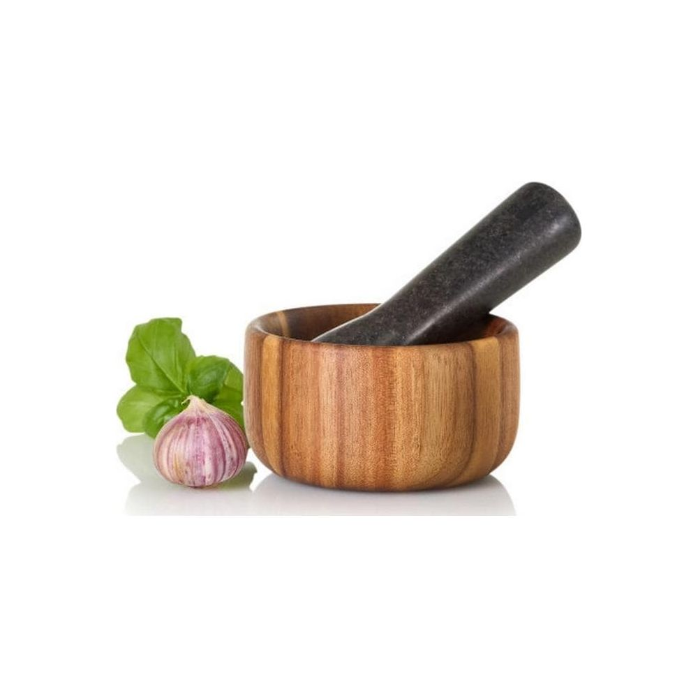 Ein hölzernen Mörser mit dunklem Stößel, Knoblauch und Basilikum auf weißem Grund.