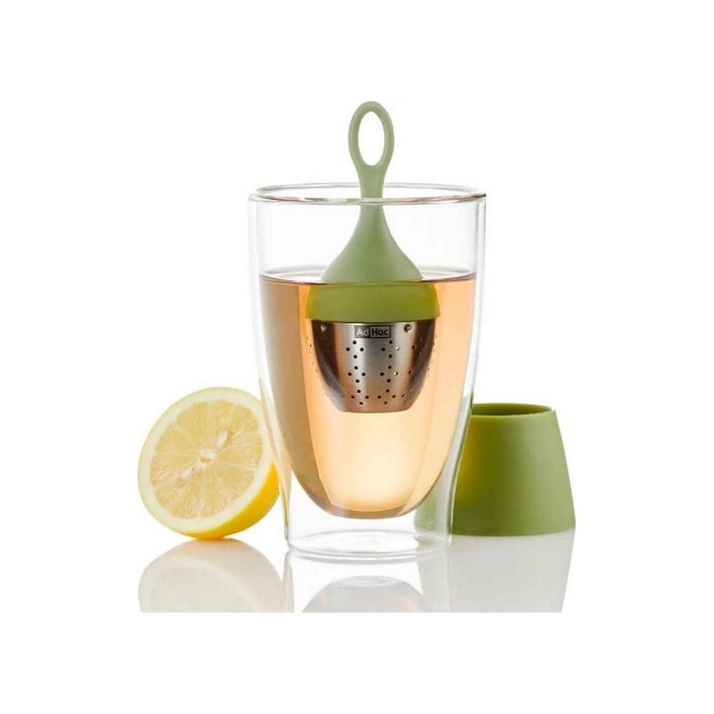 Ein Glas mit Tee, grünem Teei und einer halben Zitrone auf weißem Grund.