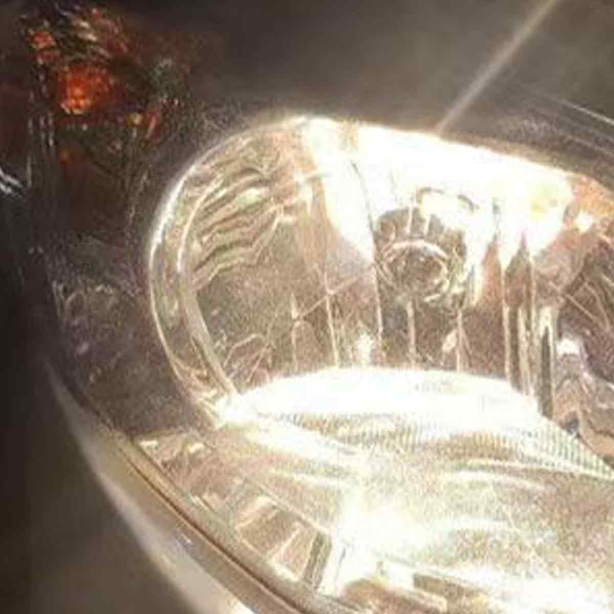 Nahaufnahme eines leuchtenden Autoscheinwerfers in der Dunkelheit.