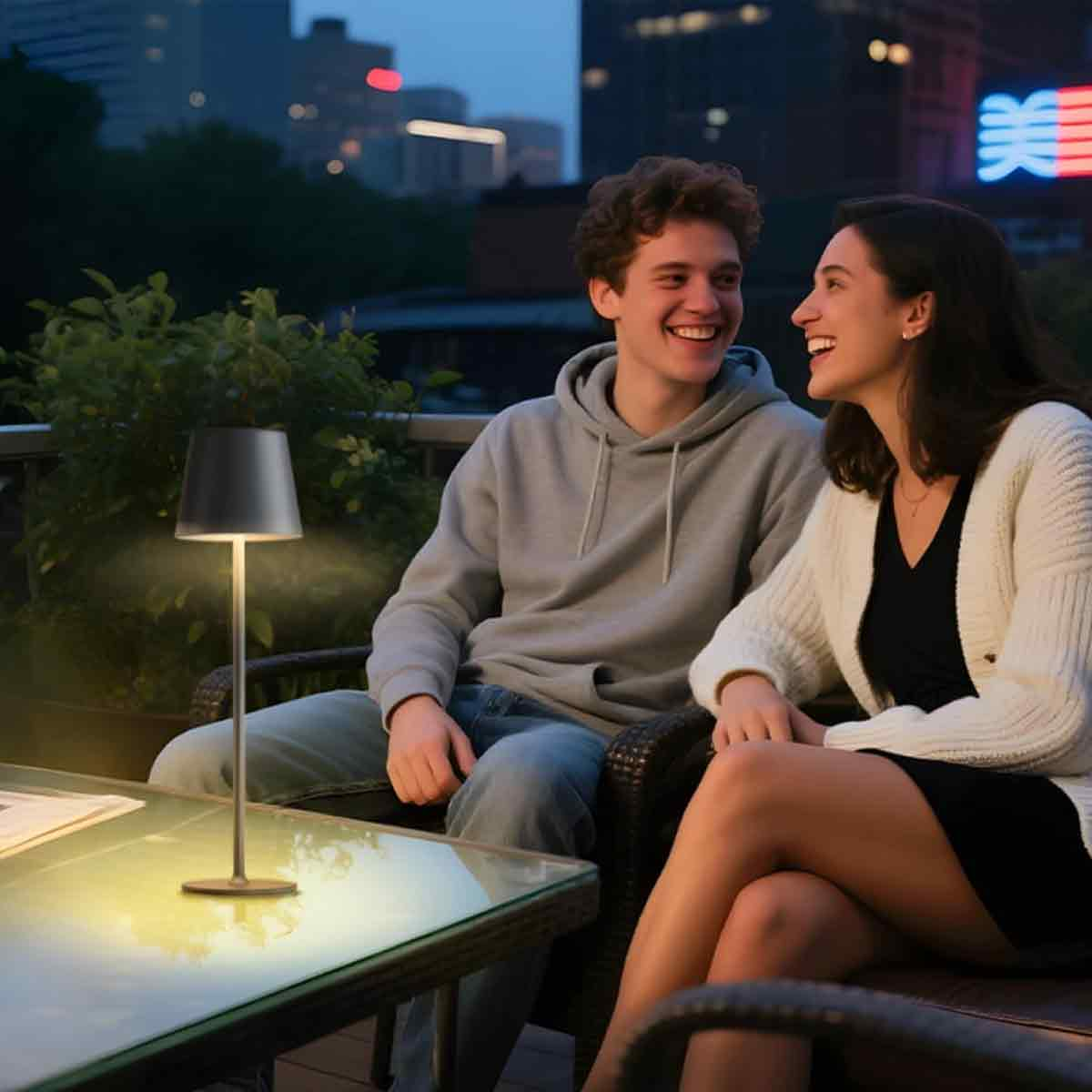 Paar sitzt auf einem beleuchteten Balkon und lächelt sich an.