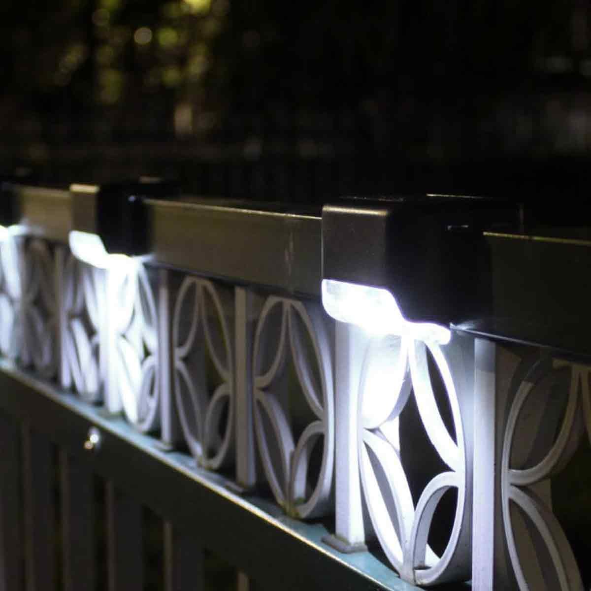 Solarlampen beleuchten ein verziertes Metallgeländer bei Nacht.