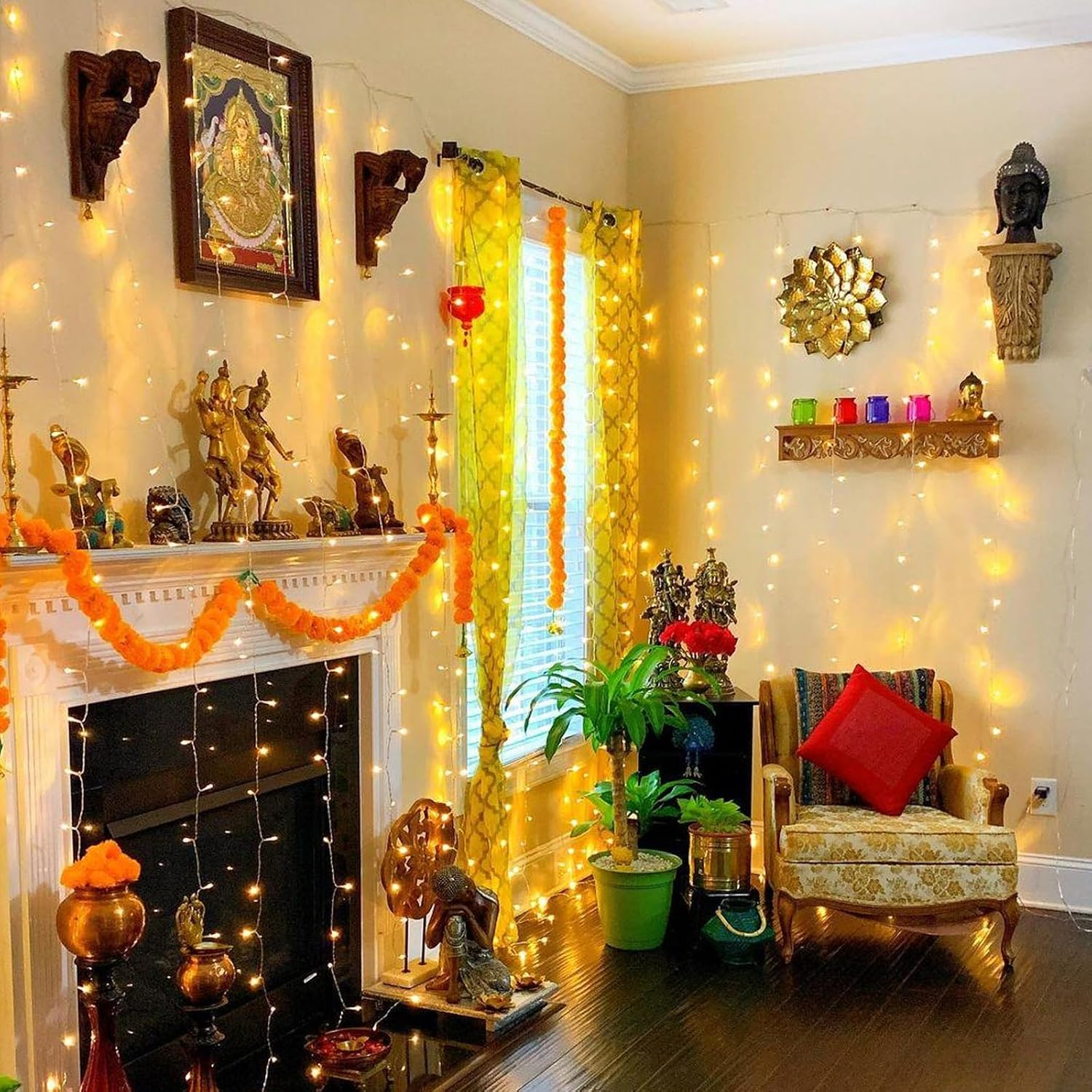 Festlich beleuchteter Raum mit Kaminsims, Buddha-Statue, Blumenkränzen und Lichterketten.