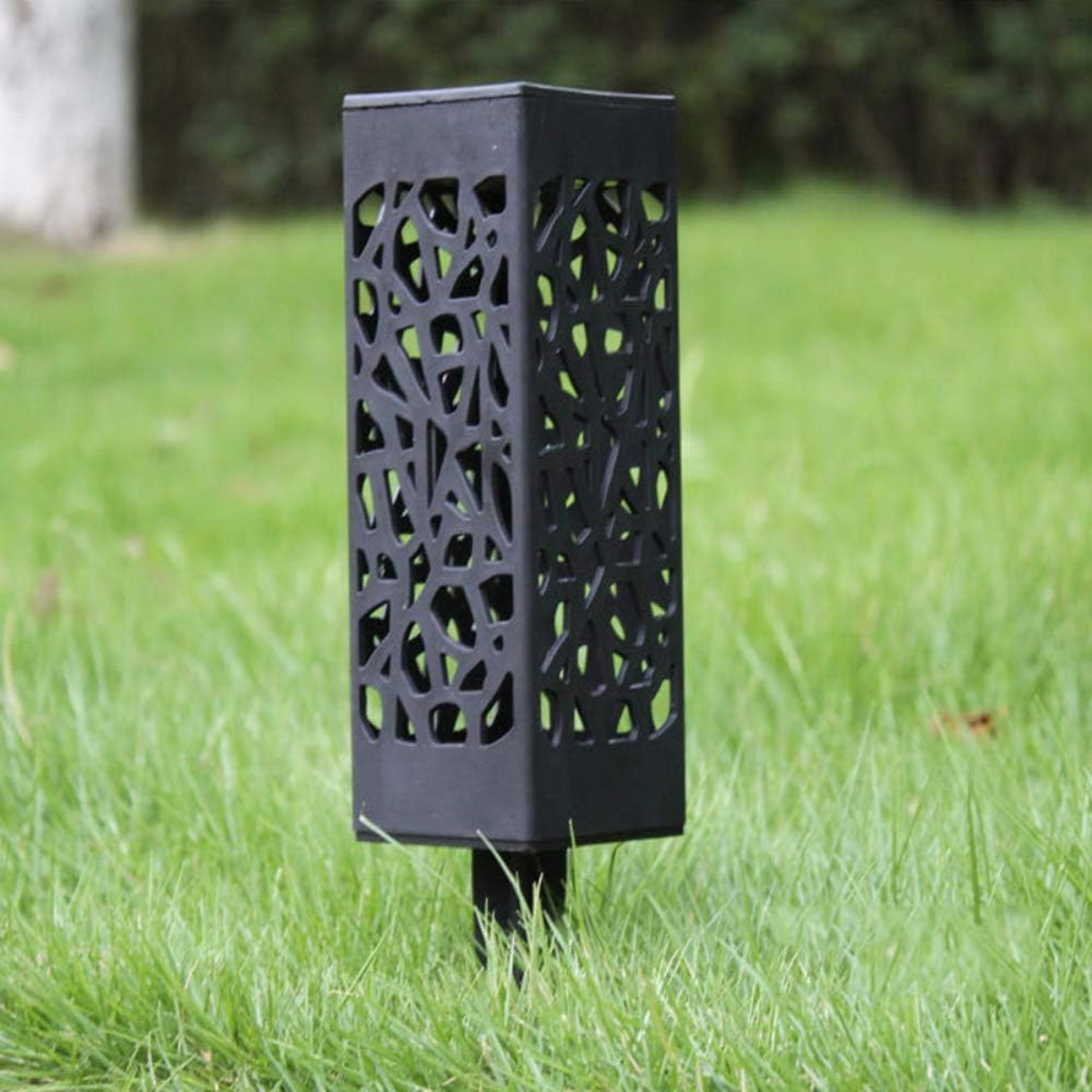 Eine schwarze Solarlampe mit dekorativem Netzmuster steht auf einer grünen Wiese.