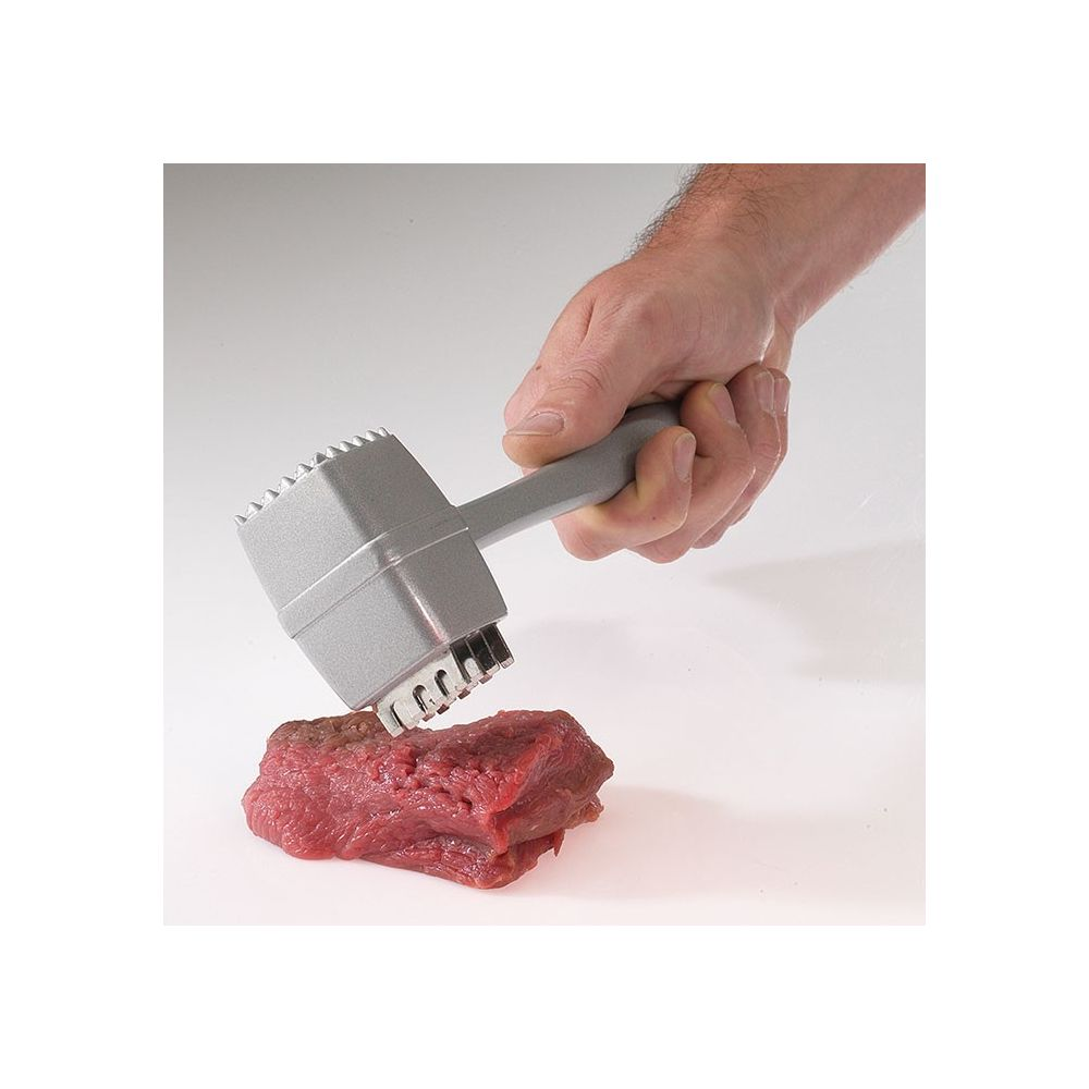 Eine Hand hält einen silbernen Fleischklopfer und klopft ein Stück rotes Fleisch.
