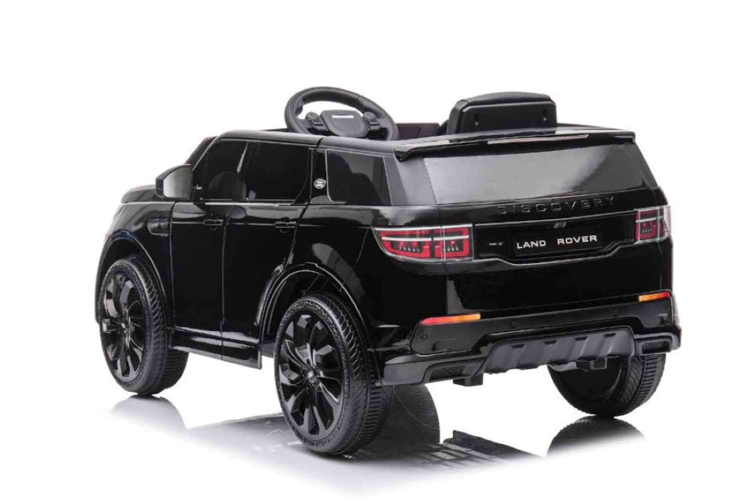 Ein glänzendes schwarzes Land Rover Kinder-Elektroauto von hinten gesehen, auf weißem Hintergrund.