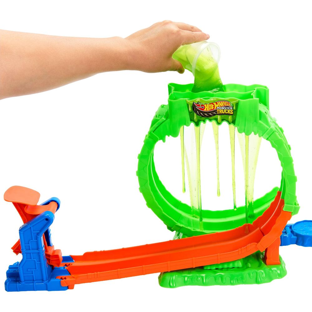Eine Hand gießt grünen Schleim in eine grüne Hot Wheels Monster Trucks Spielset-Schleife.