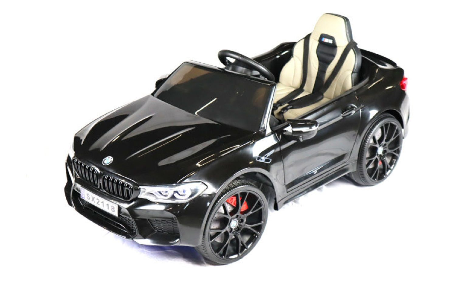Ein schwarzes Elektro-Spielzeugauto für Kinder mit beigem Interieur und schwarzen Rädern, freigestellt auf weißem Grund.