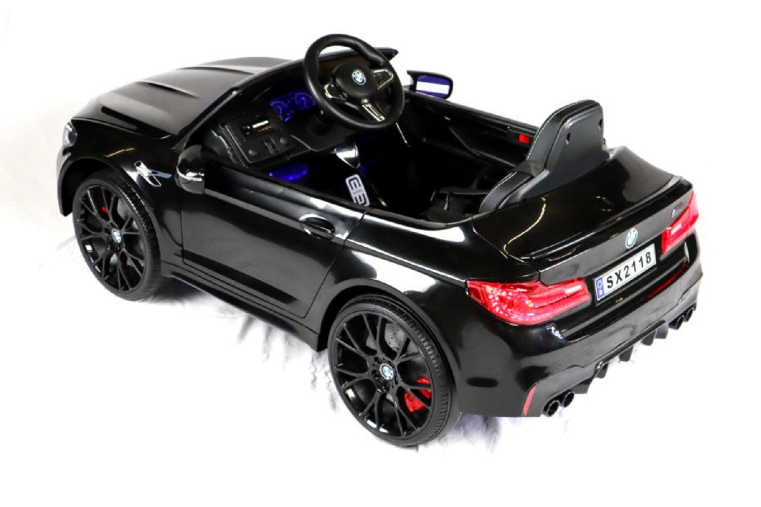 Ein glänzendes schwarzes Kinder-Elektroauto in BMW-Optik auf weißem Hintergrund.