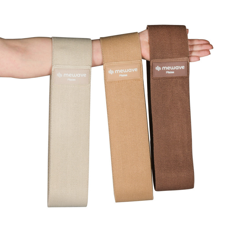 Brazo sosteniendo tres bandas de resistencia de Pilates marrones y beiges.