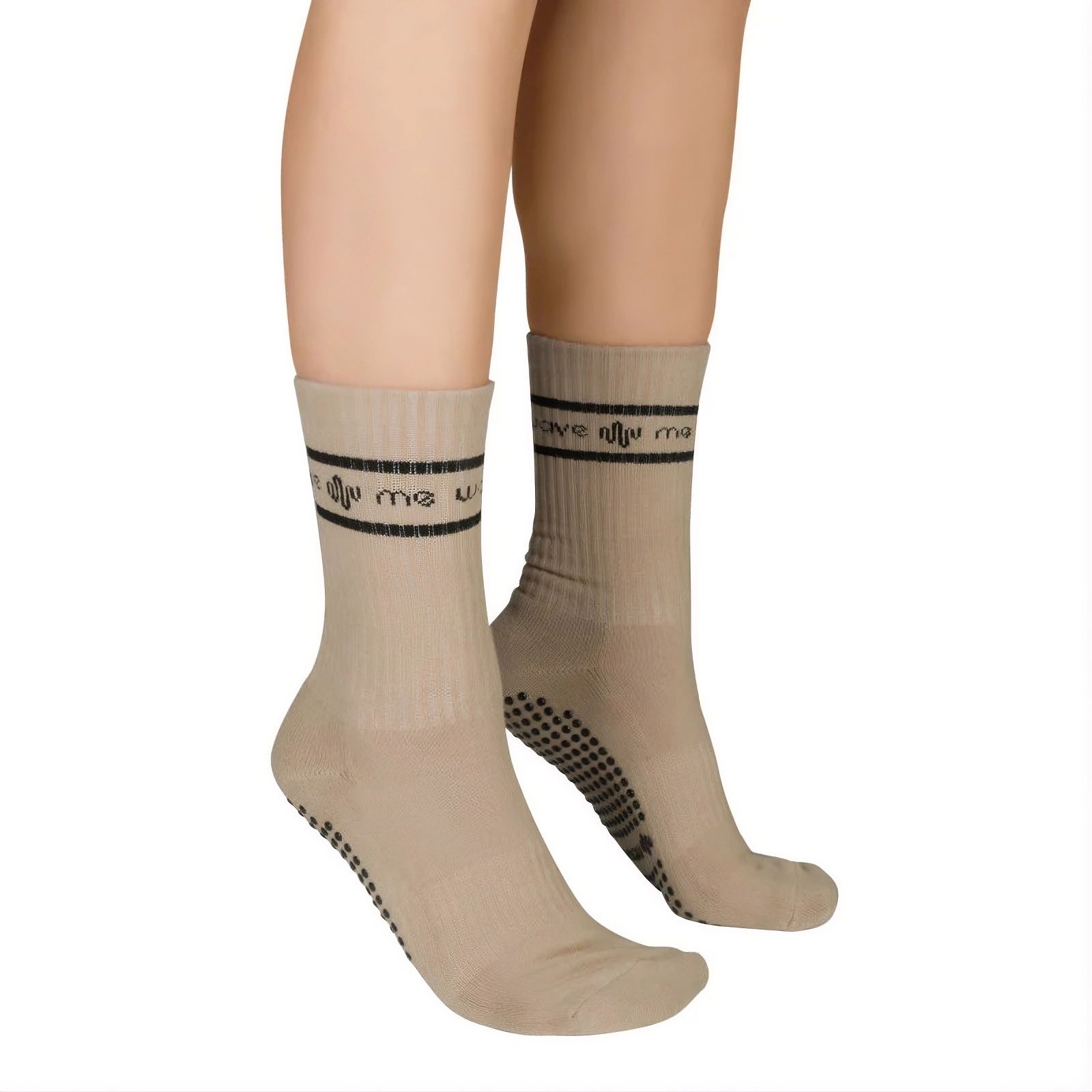 Primer plano de piernas con calcetines antideslizantes beis con texto negro y rayas sobre fondo blanco.