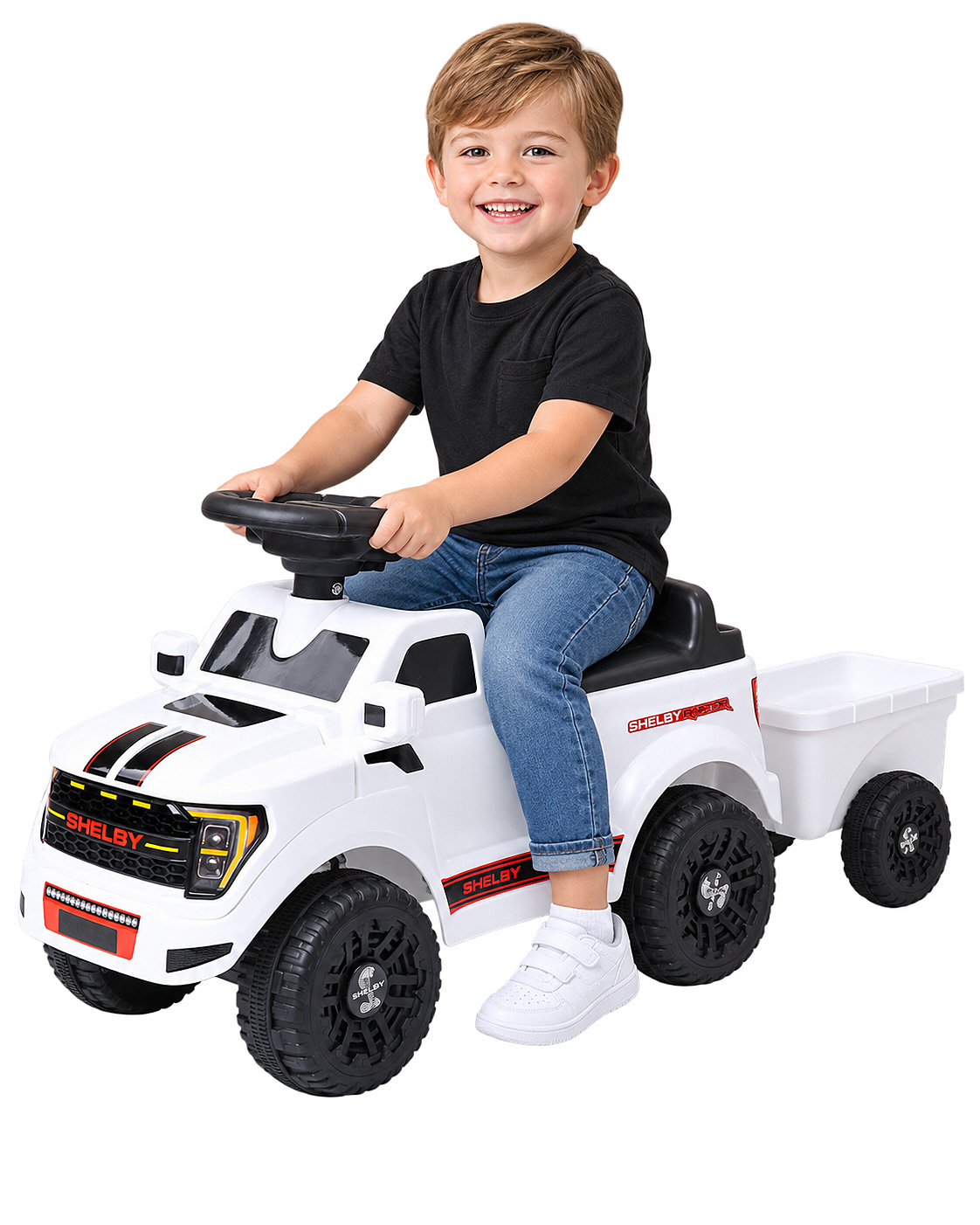 Ein glücklicher Junge sitzt auf einem weißen Shelby-Spielzeugauto mit Anhänger.