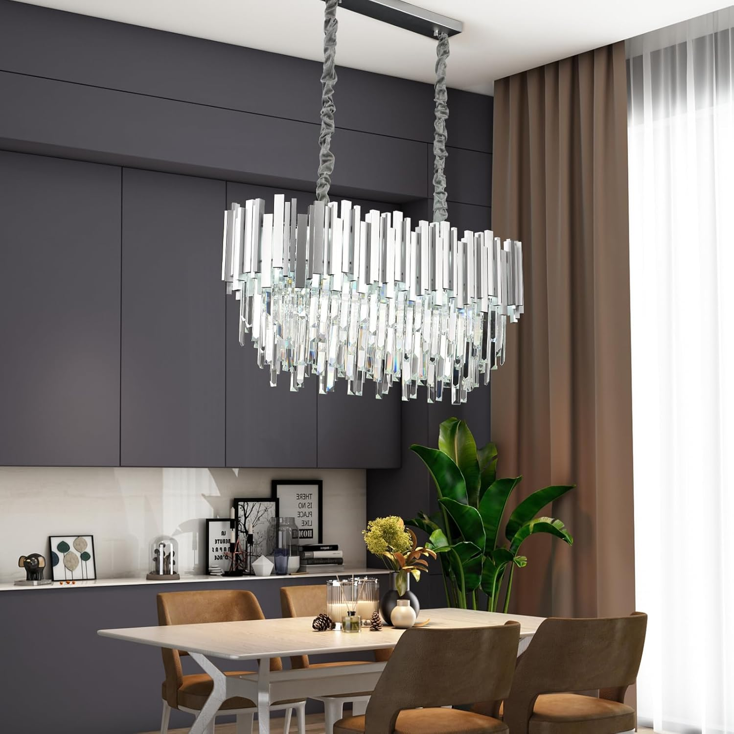 Ein modernes Esszimmer hat einen großen Kristallleuchter, einen hellen Holztisch mit braunen Stühlen und graue Schränke.