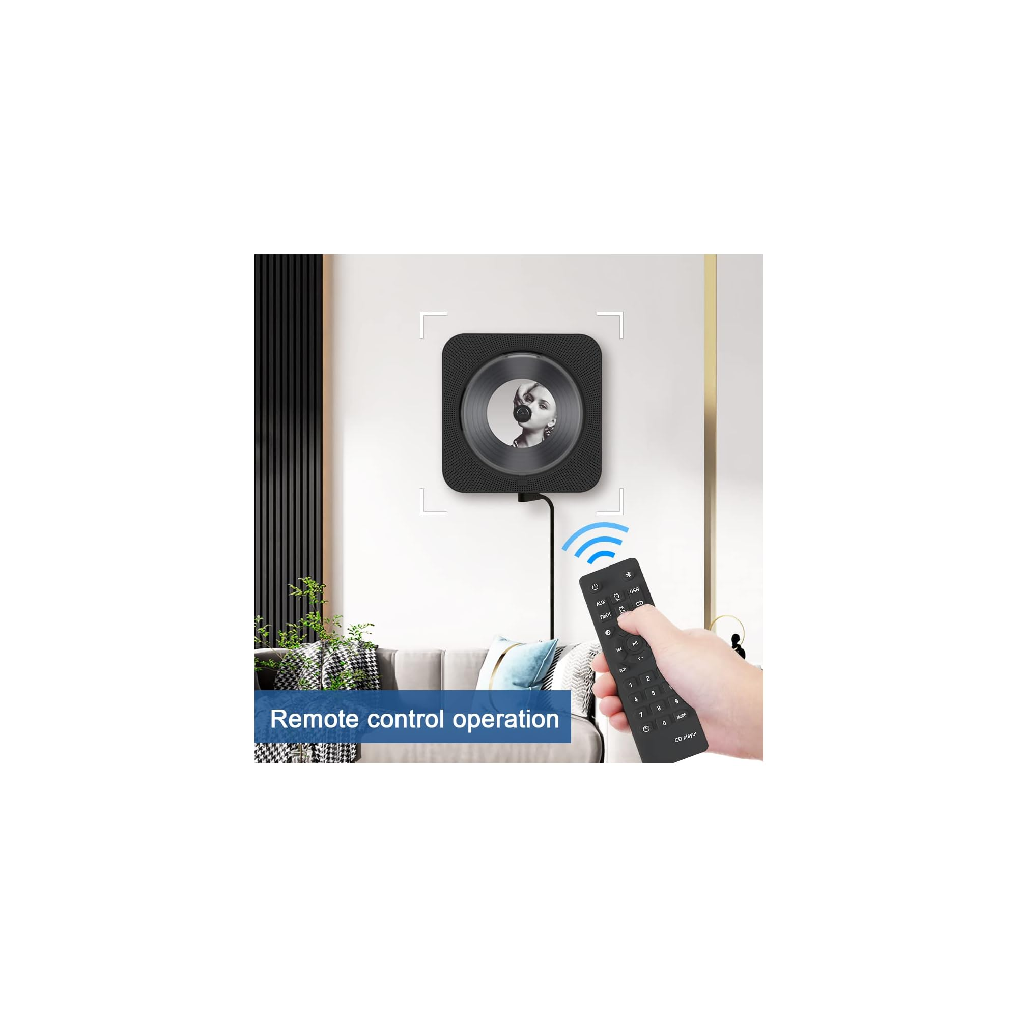 Hand hält Fernbedienung für einen wandmontierten schwarzen CD-Player im Wohnzimmer.