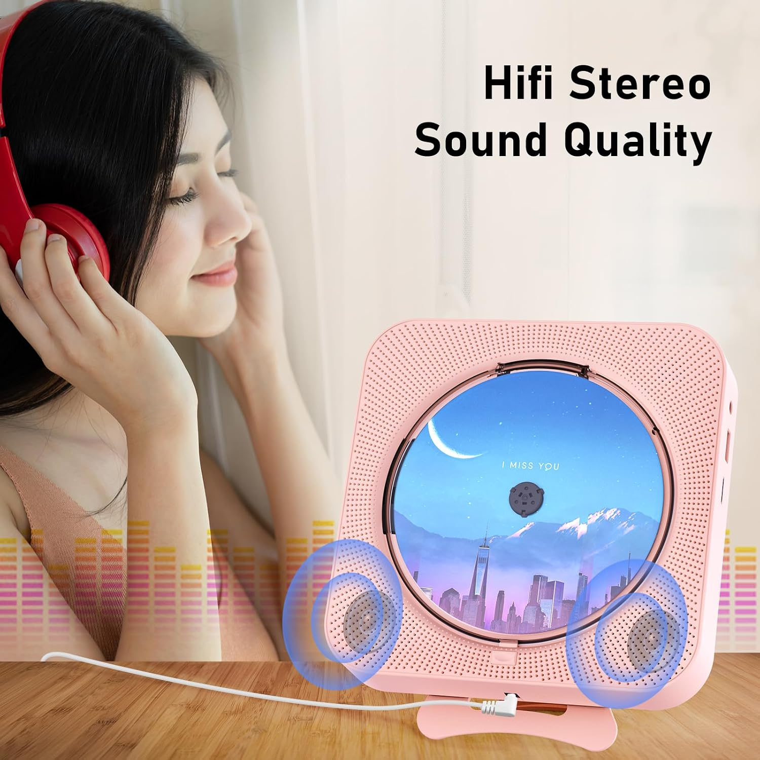 Eine Frau mit roten Kopfhörern sitzt neben einem pinken CD-Player auf einem Holztisch.