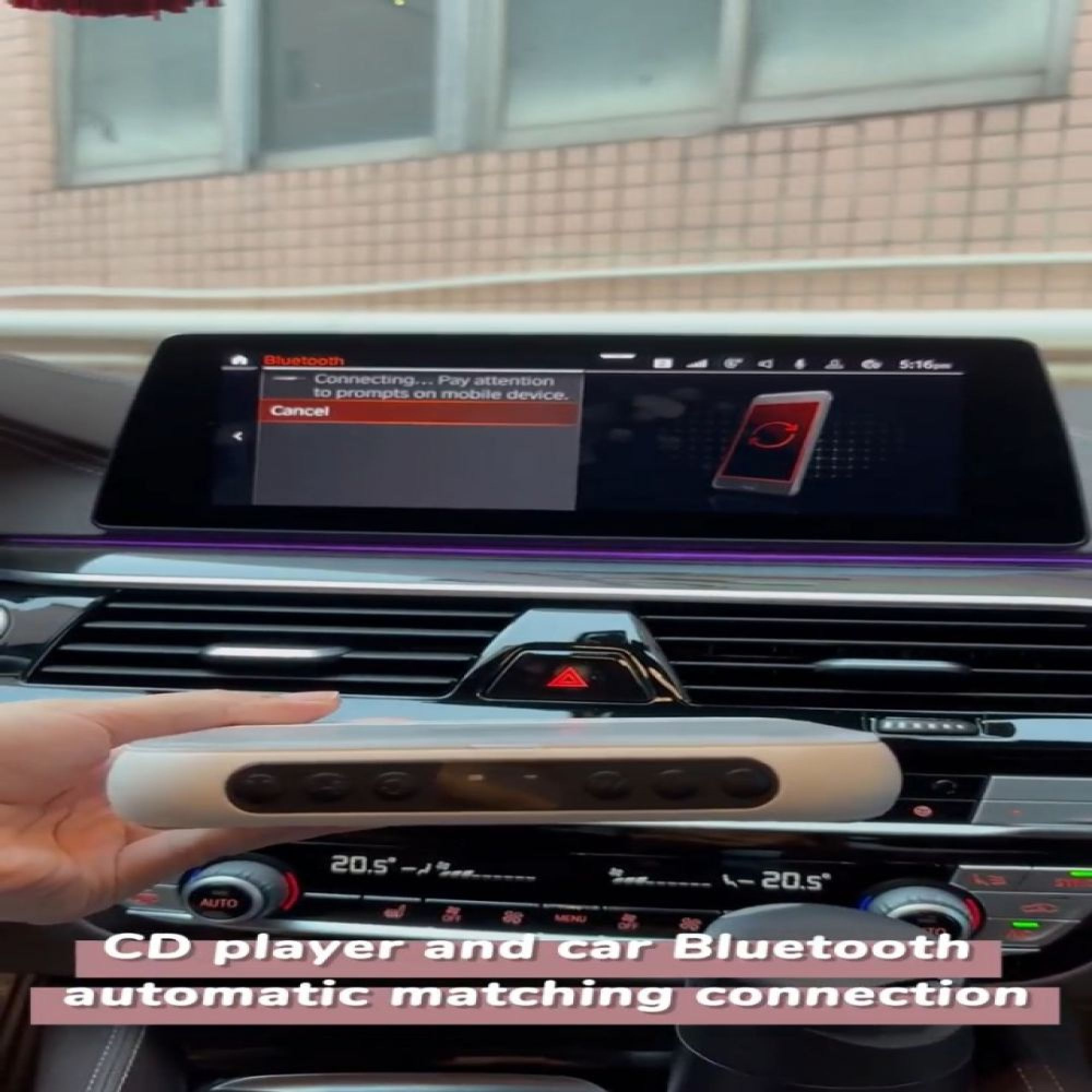 Eine Hand hält ein Gerät in einem Auto mit einem Bildschirm, der eine Bluetooth-Verbindung anzeigt.