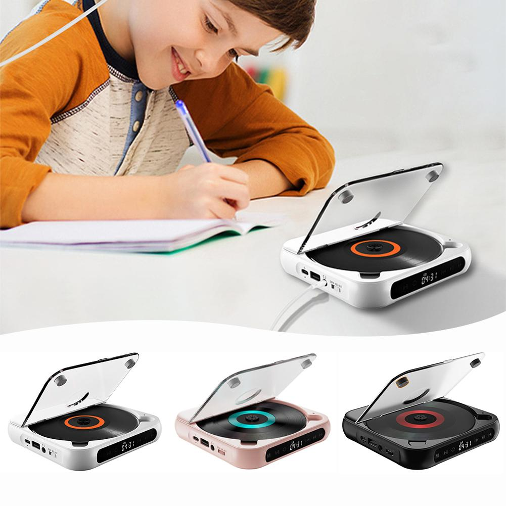 Ein Junge schreibt in ein Heft, neben ihm steht ein kompakter CD-Player in verschiedenen Farben.