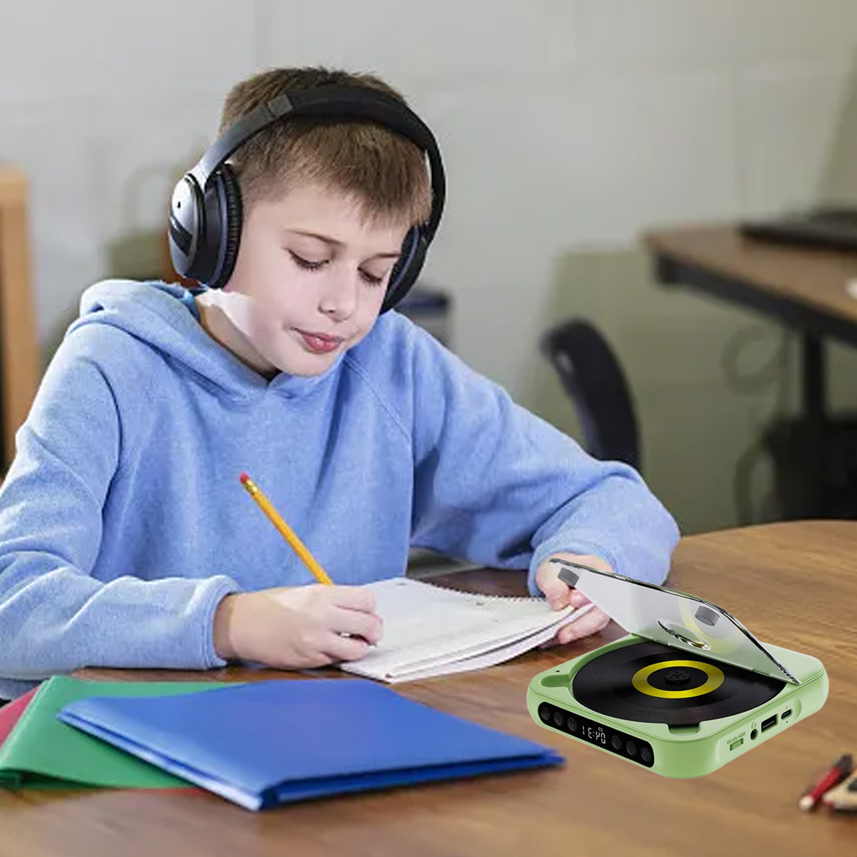 Ein Junge mit Kopfhörern schreibt an einem Holztisch, daneben ein tragbarer CD-Player.