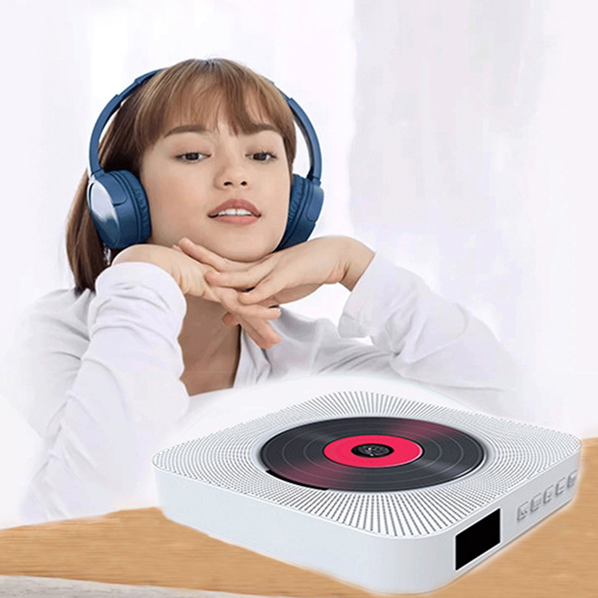 Eine Frau mit blauen Kopfhörern hört Musik, vor ihr steht ein weißer tragbarer CD-Player auf dem Tisch.