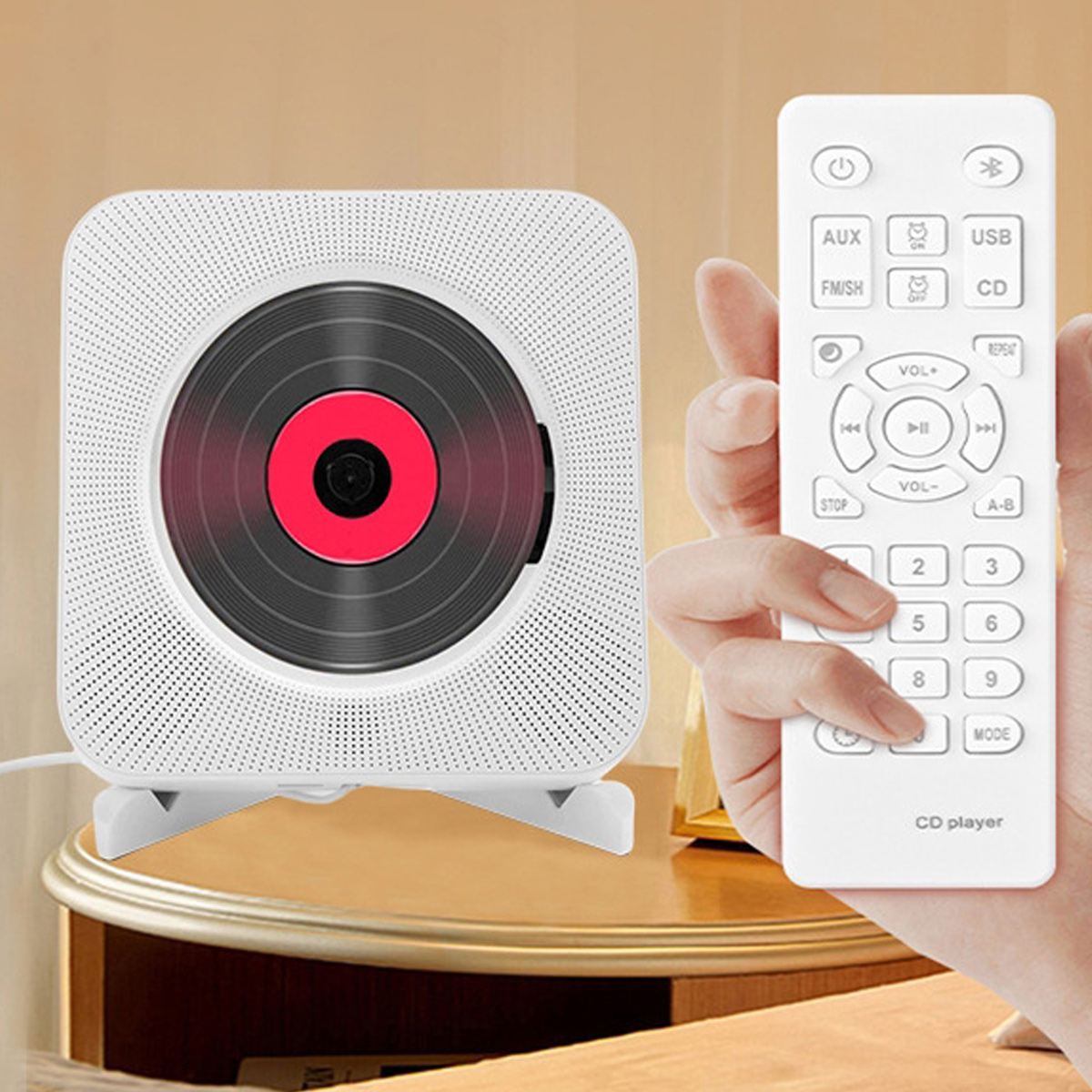 Ein weißer CD-Player mit einer dunklen Disc und eine Hand, die eine weiße Fernbedienung hält.