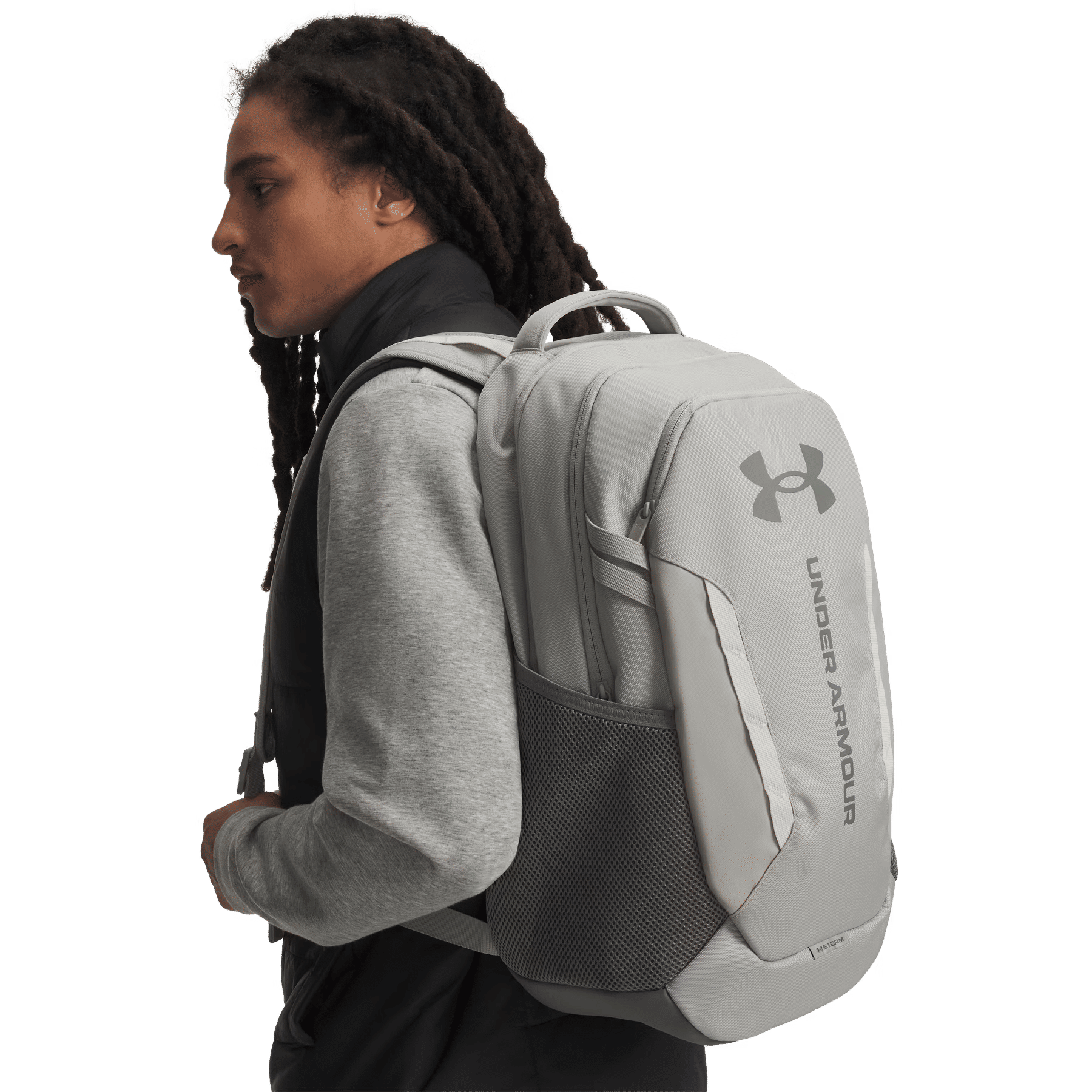 Ein Mann mit Dreadlocks und einem grauen Rucksack vor schwarzem Hintergrund.