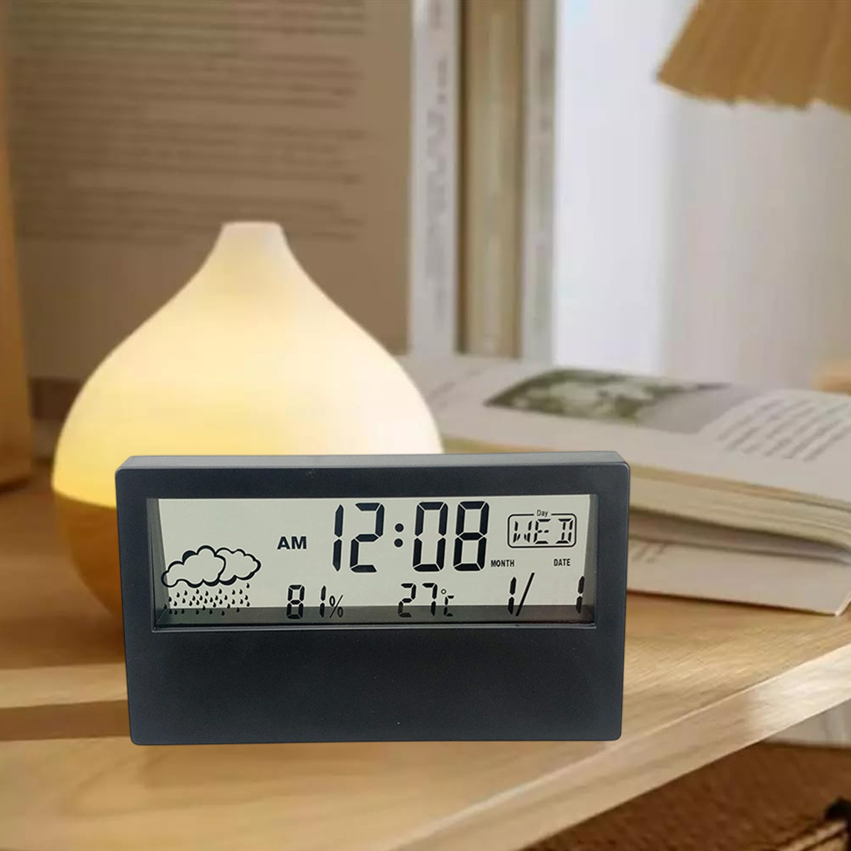 Eine schwarze digitale Wetteruhr auf einem Holztisch zeigt Uhrzeit, Regensymbol, Luftfeuchtigkeit, Temperatur und Datum.