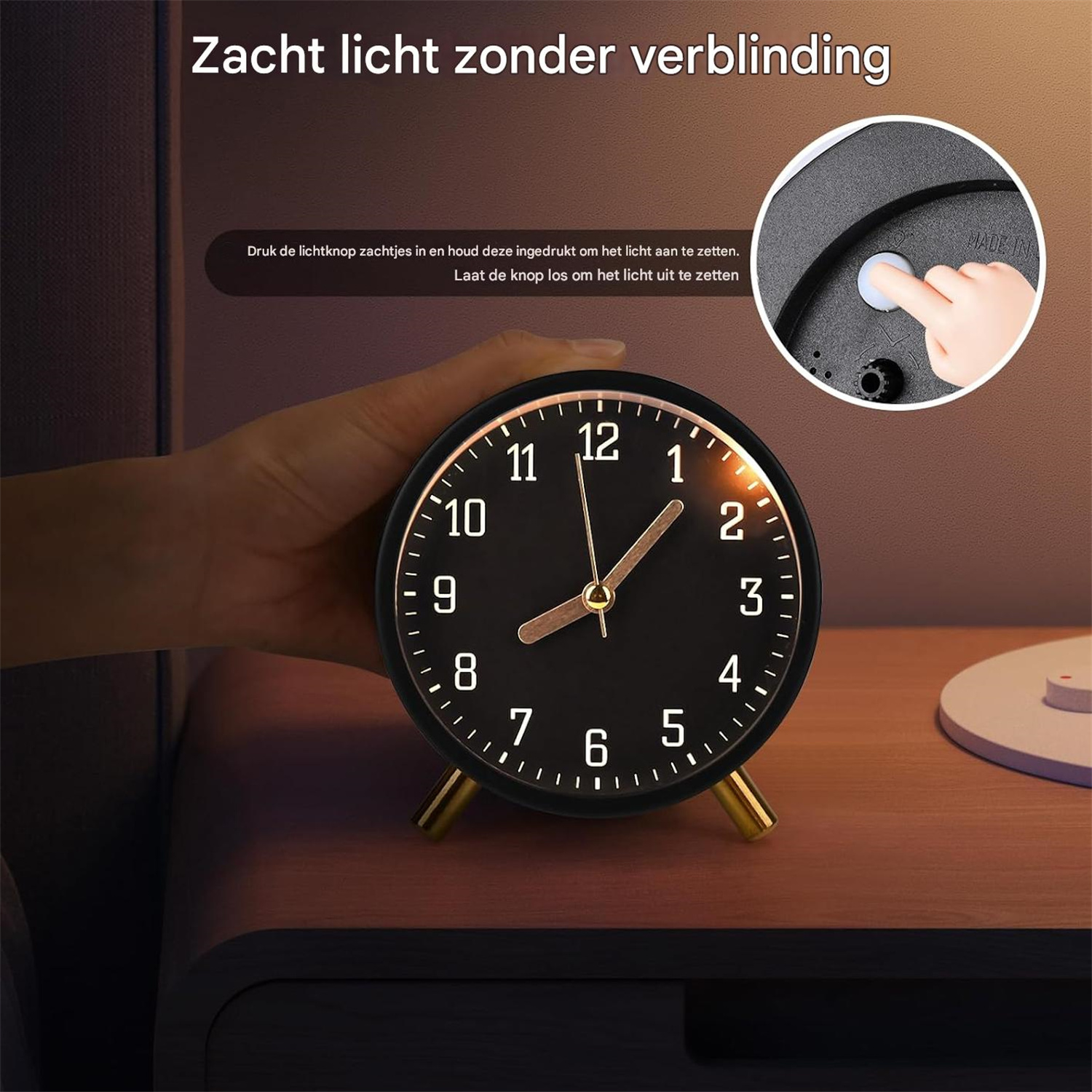 Ein schwarzer Tischwecker mit goldenen Beinen und Zeigern steht auf einem Holztisch.