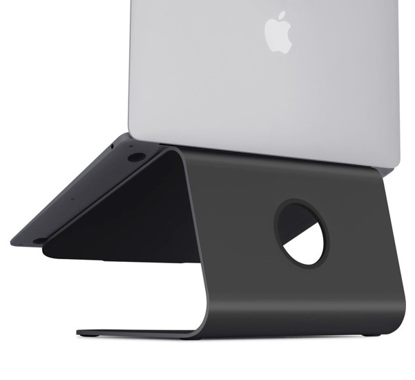 Een zilveren laptop op een zwarte, gebogen metalen standaard tegen een witte achtergrond.