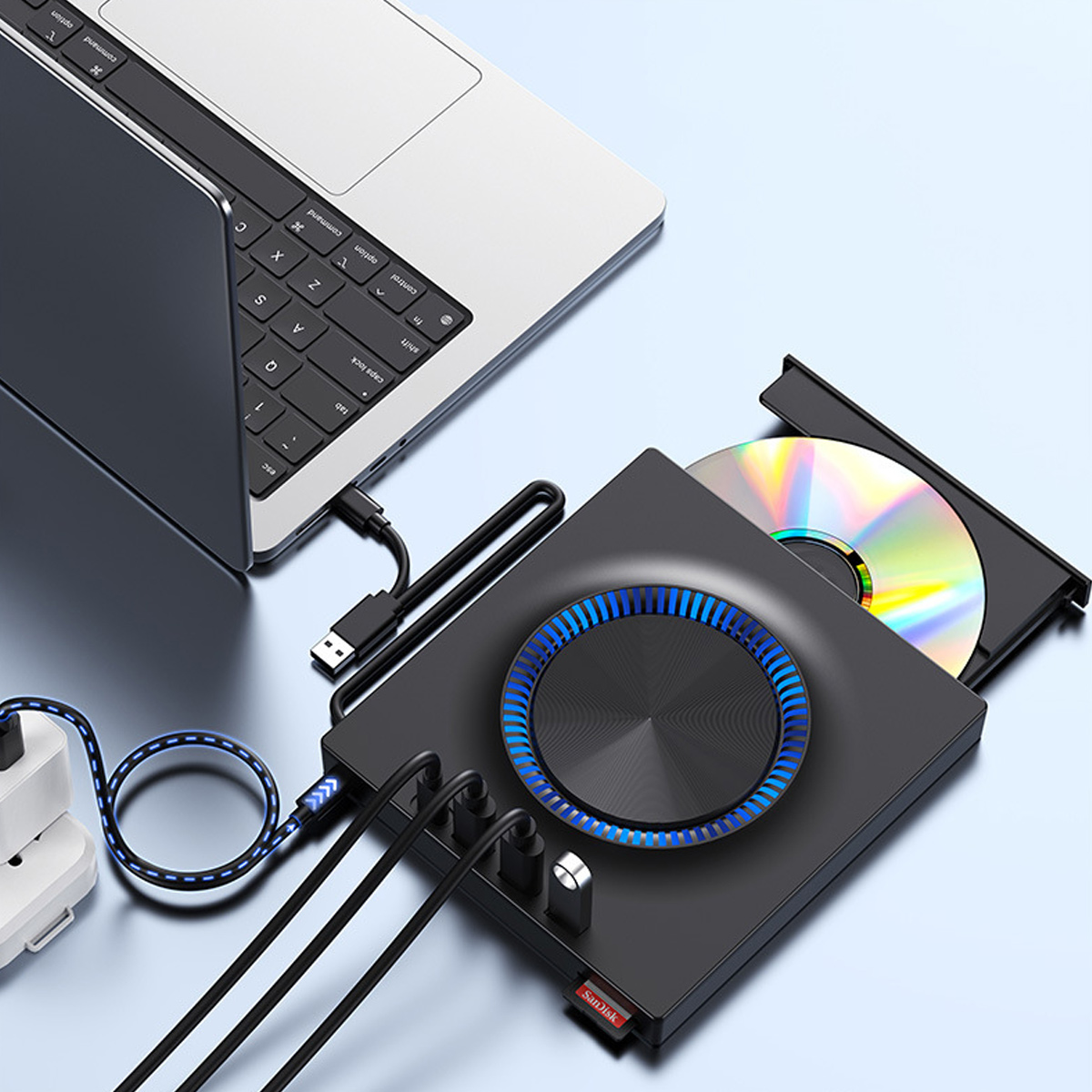 Ein schwarzes optisches Laufwerk mit blauer LED und eingelegter CD ist über Kabel mit einem silbernen Laptop verbunden.