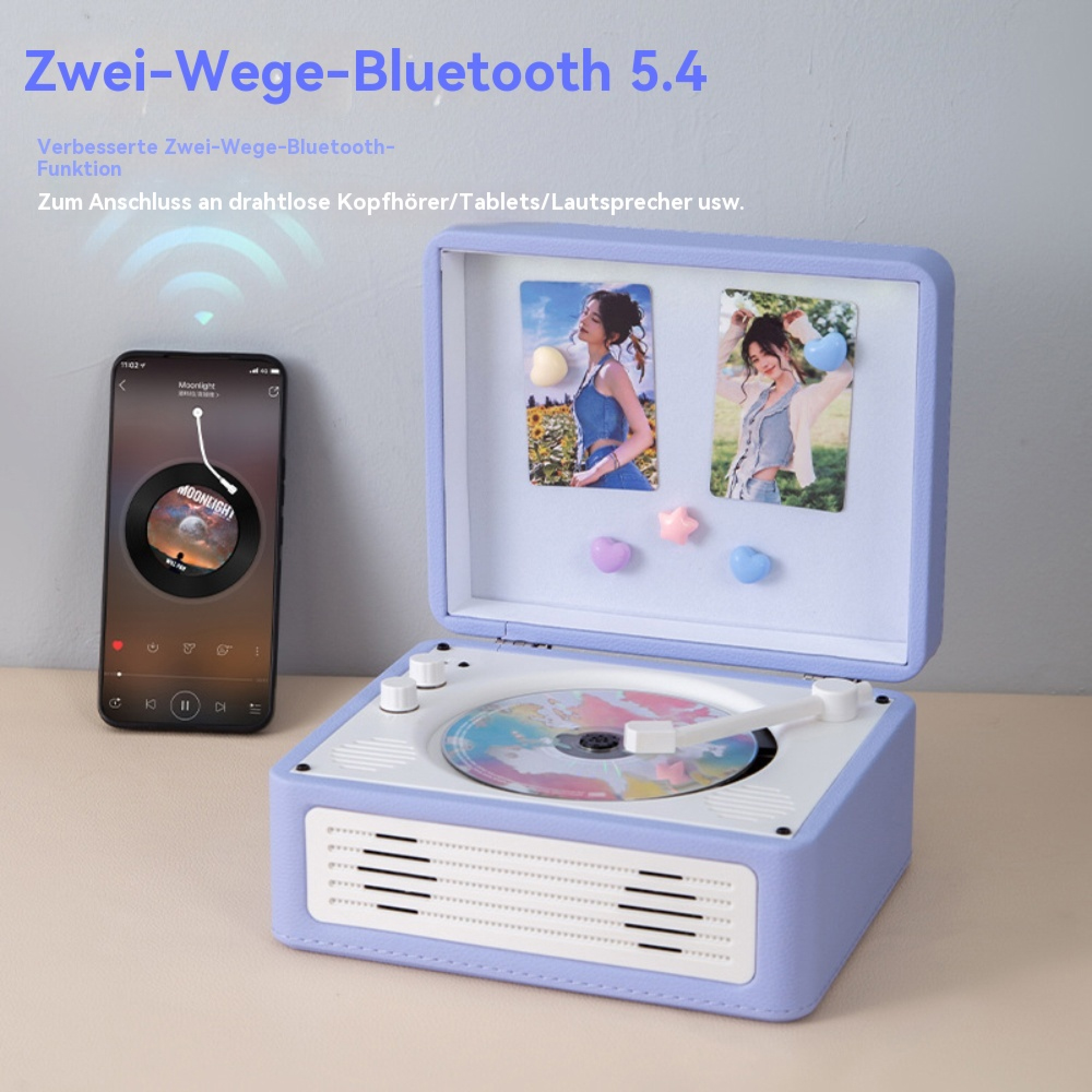 Ein lila Plattenspieler mit integriertem Lautsprecher, ein Smartphone daneben und Fotos im Deckel.