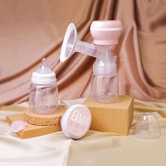 Eine elektrische Milchpumpe mit Flasche, Babyflasche und Steuereinheit auf beigem Stoff.