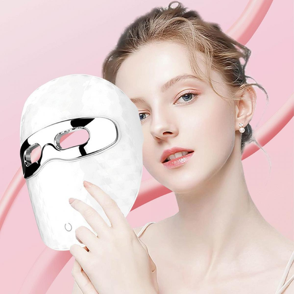 Eine Frau hält eine weiße LED-Gesichtsmaske vor ihr Gesicht vor einem rosa Hintergrund.