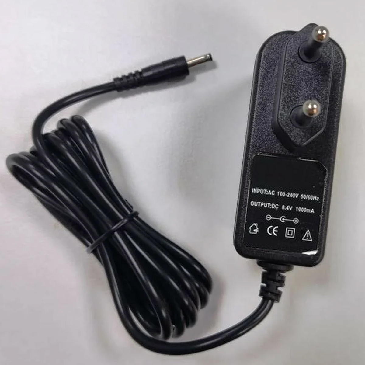 Schwarzes Netzteil mit EU-Stecker und aufgewickeltem Kabel auf weißem Grund.
