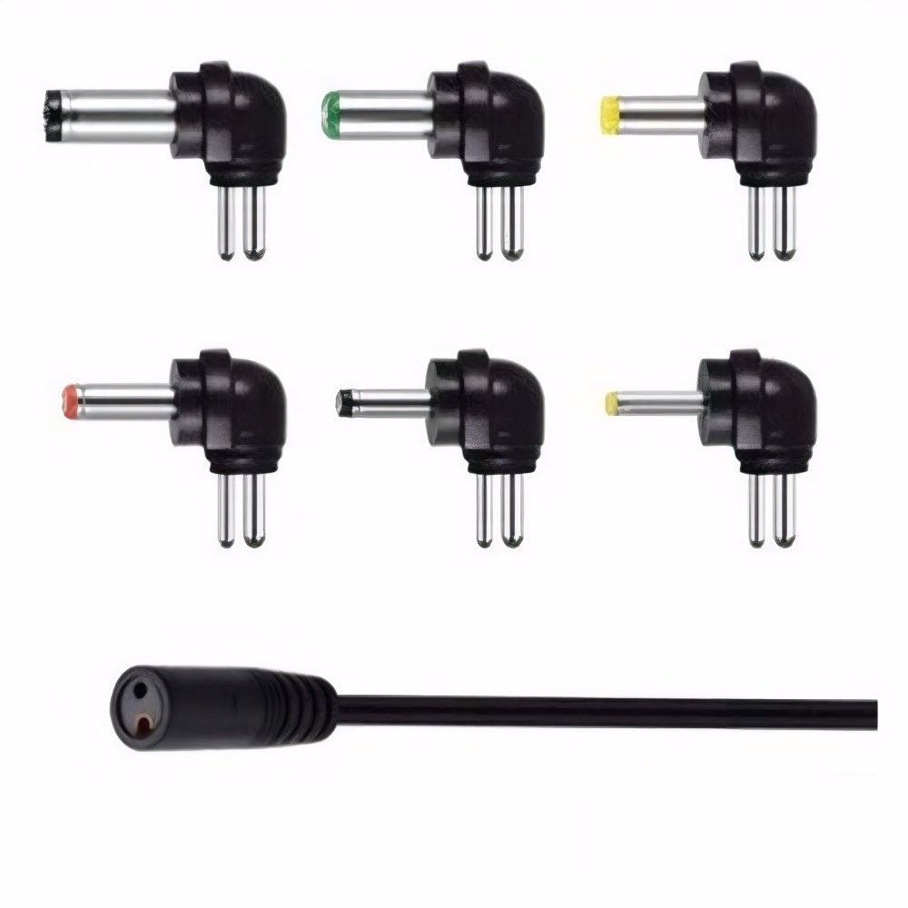 Sechs schwarze rechtwinklige DC-Netzteil-Adapterstecker mit verschiedenfarbigen Spitzen und ein schwarzes Kabel auf weißem Grund.