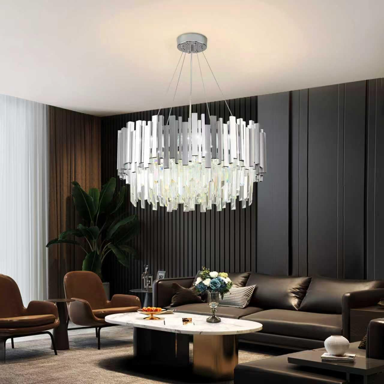 Moderner Kronleuchter hängt in einem stilvollen Wohnzimmer mit dunklen Wänden und Ledersofas.