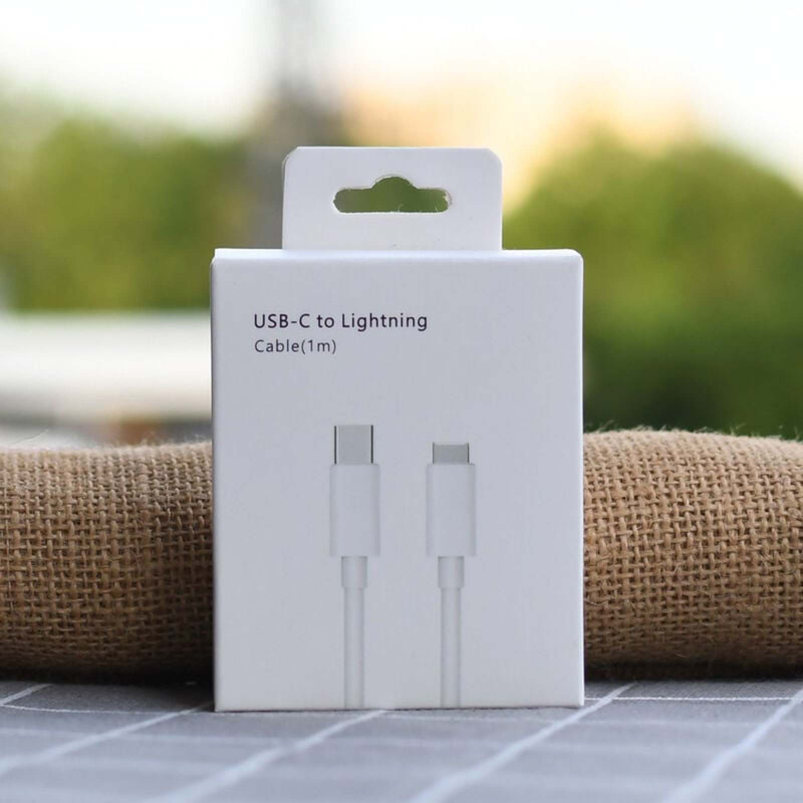 Eine weiße Verpackung für ein USB-C-zu-Lightning-Kabel auf einer Tischoberfläche mit weichem Hintergrund.