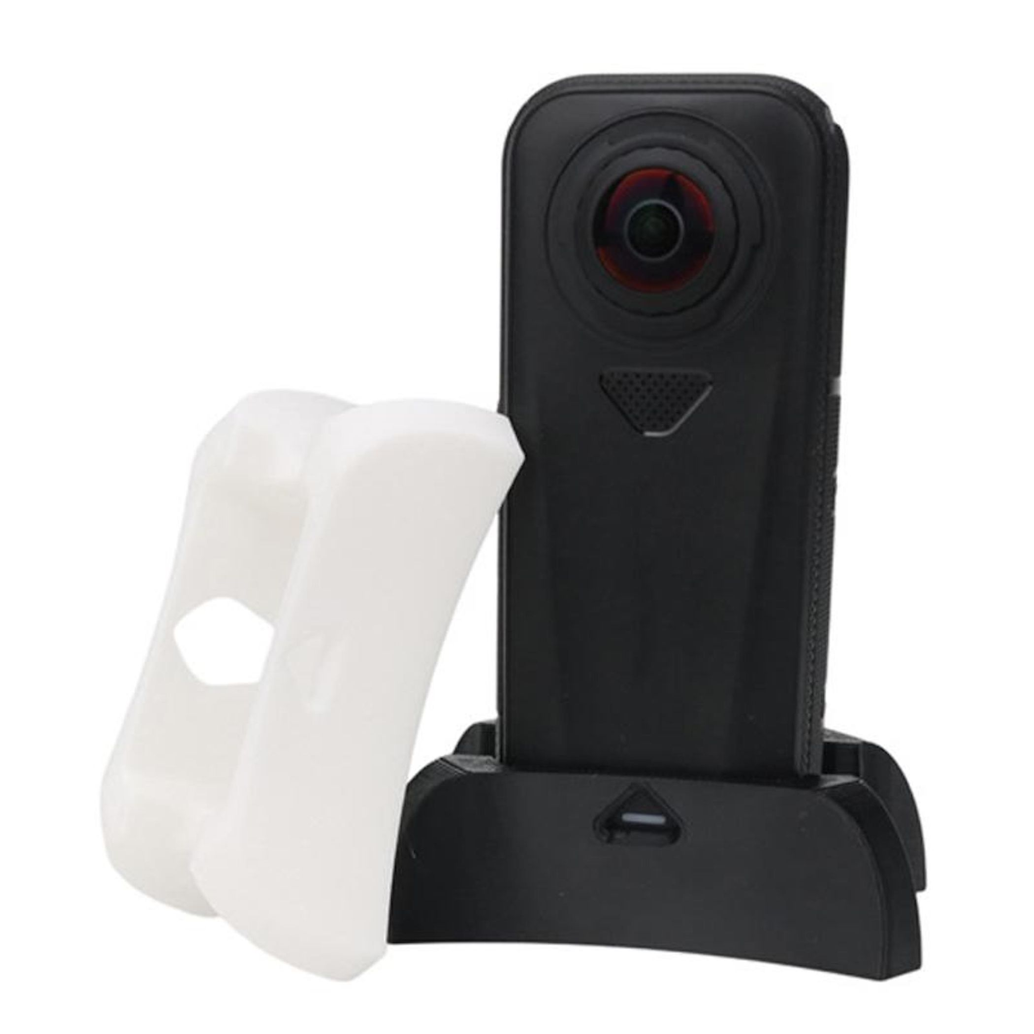 Eine schwarze 360-Grad-Kamera steht in ihrer Ladeschale neben einer weißen Silikonschutzhülle.
