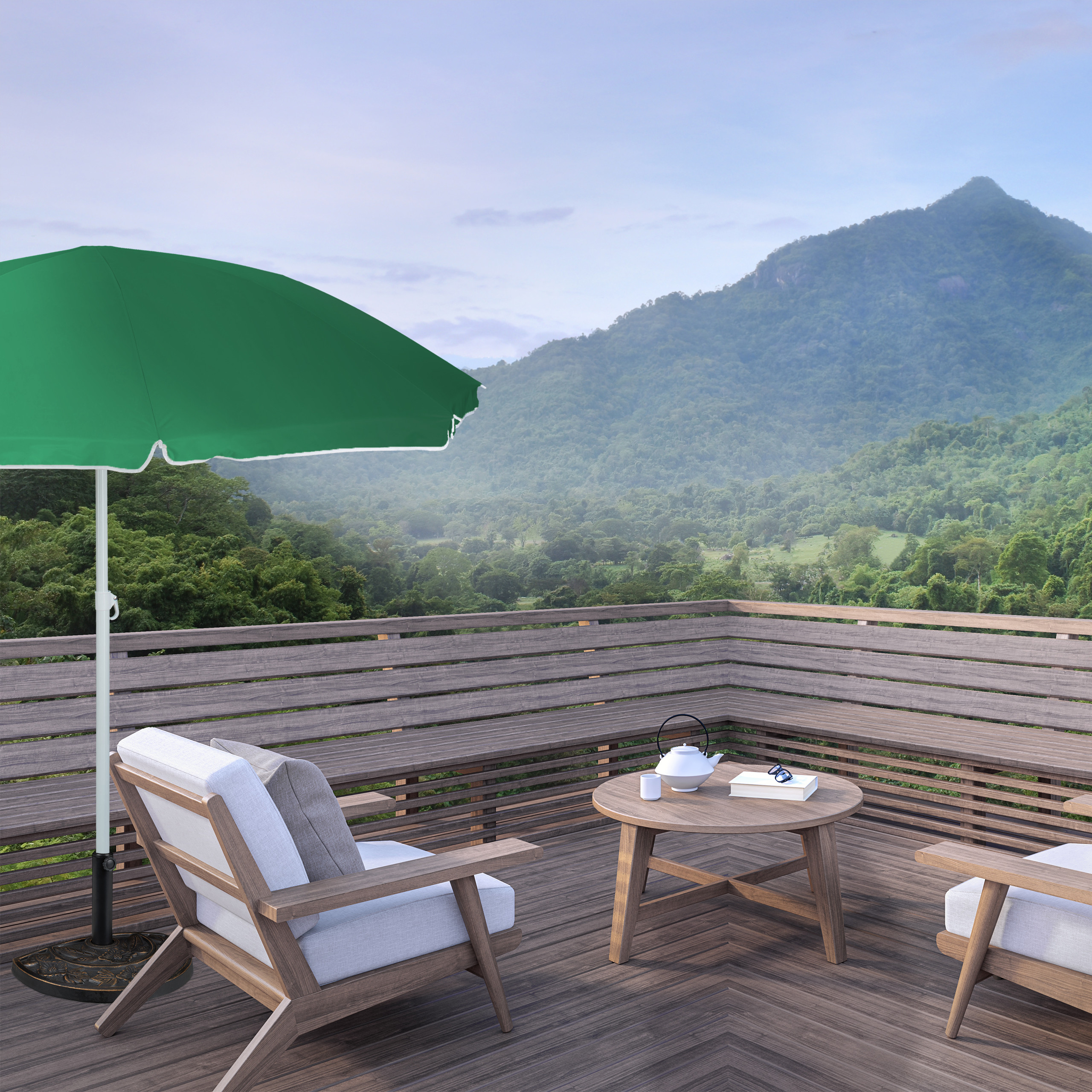 Holzterrasse mit Sesseln, Tisch und grünem Sonnenschirm vor einer bergigen Waldlandschaft.