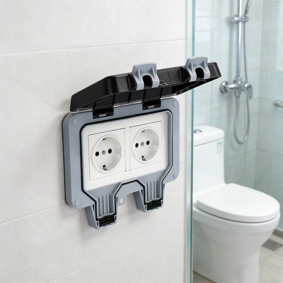 Wasserdichte Doppelsteckdose mit offener Schutzklappe an heller Wand im Badezimmer mit Toilette.