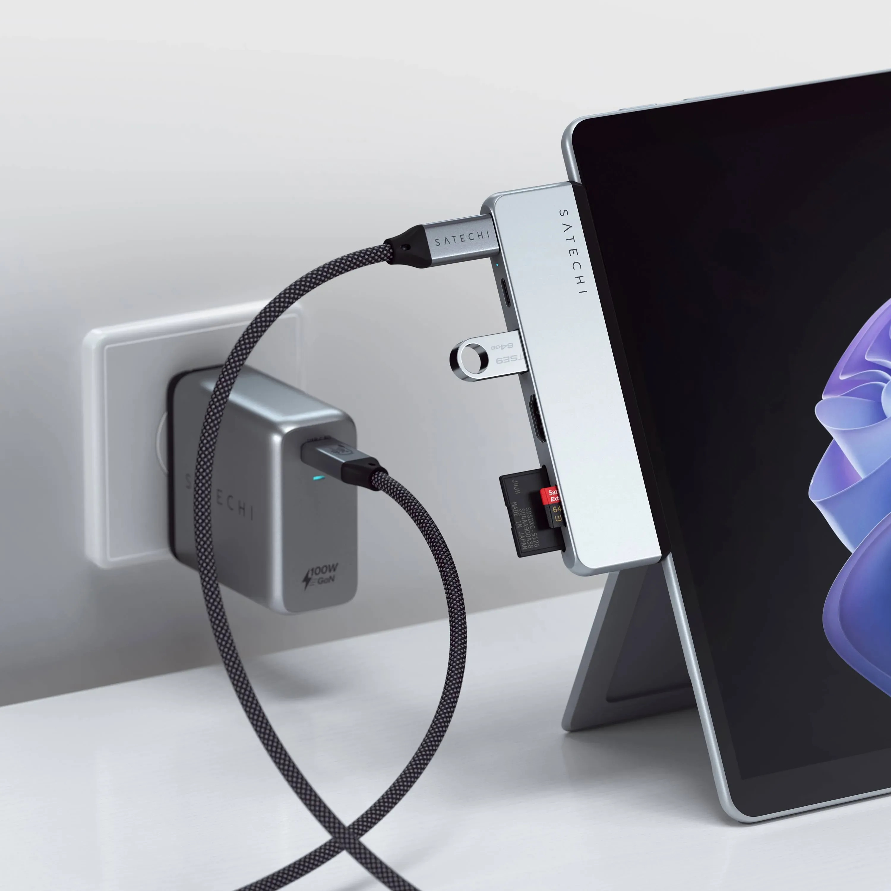 Hub Satechi z pamięcią USB i kartą SD jest podłączony do tabletu i ładowarki ściennej.