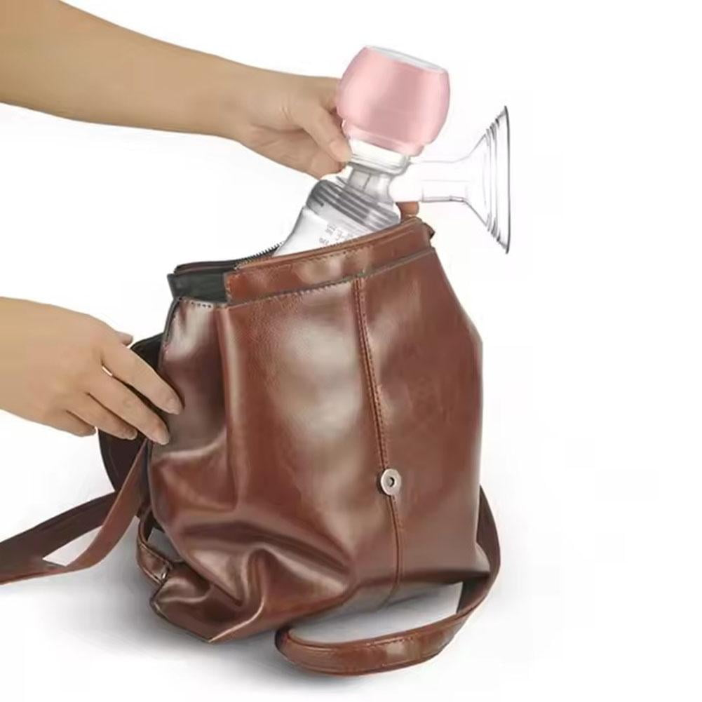 Eine Person legt eine rosa-transparente elektrische Milchpumpe in einen braunen Lederrucksack.