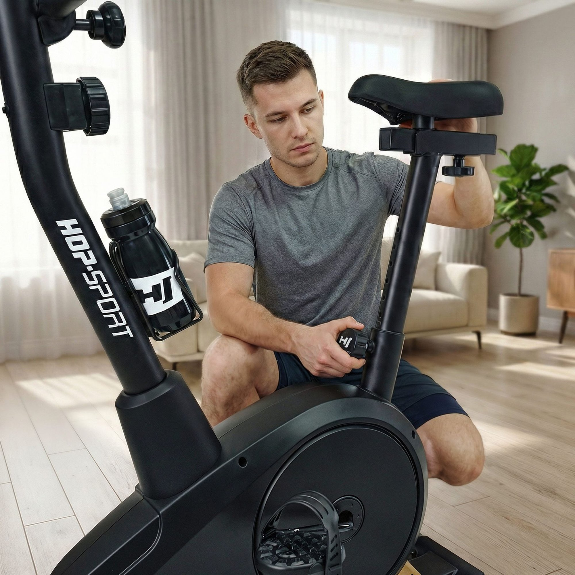 Ein Mann im grauen T-Shirt adjustiert den Sattel eines schwarzen Heimtrainers in einem hellen Wohnzimmer.