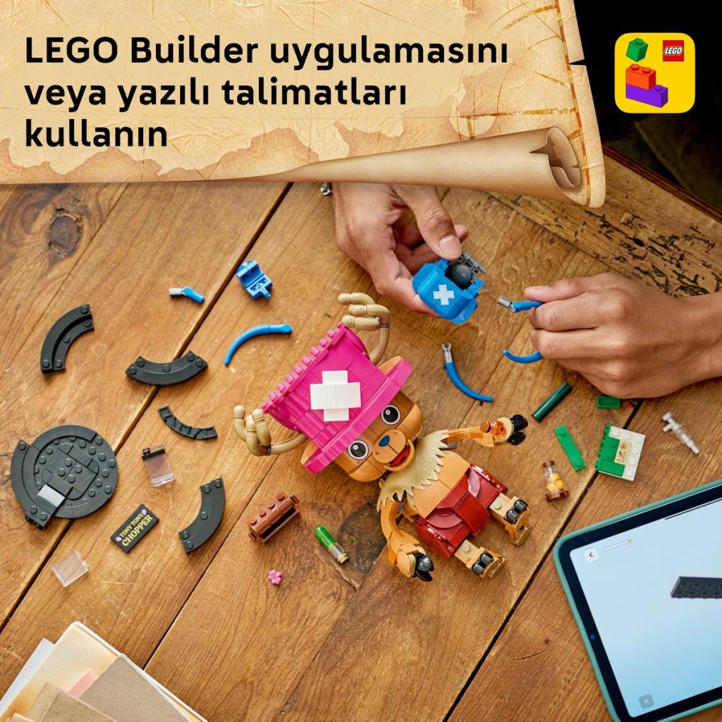 Manos construyendo un Chopper LEGO de One Piece en una mesa de madera con tablet.