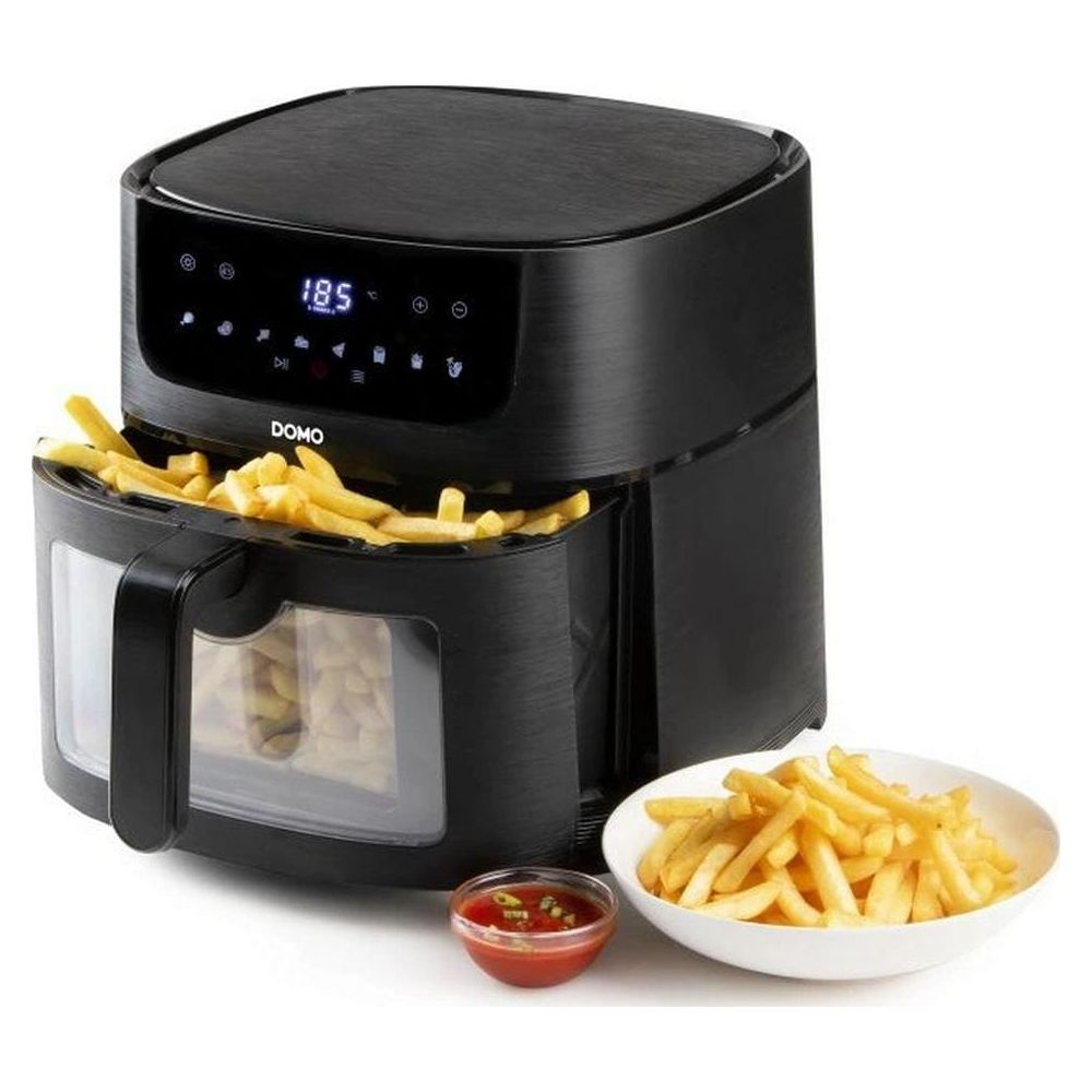 Friteuse à air noire avec des frites dans le panier, à côté d'un bol de frites et de ketchup.